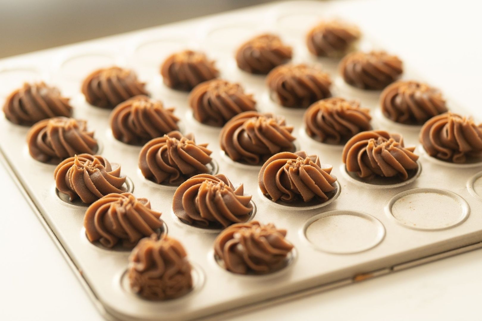 Spritsade chokladbruna kaffekrämsklickar på en metallbricka